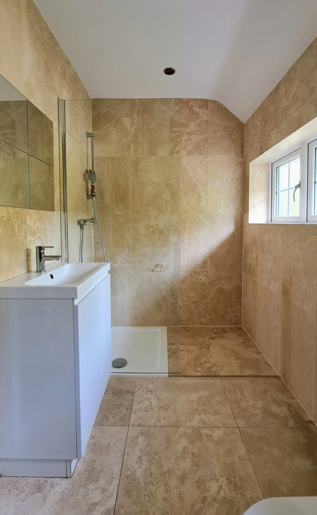 Travertine-tiled bathroom with walk-in shower area, South London — Fellner Construction